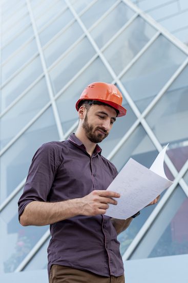 worker with orange helmet reading schematic